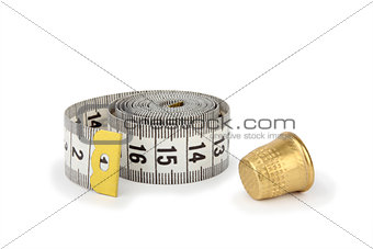 Gray measuring tape and thimble on white