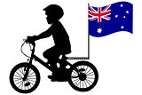A kid rides a bicycle with Australia flag