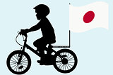 A kid rides a bicycle with Japan flag