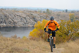 Cyclist Riding Bike on the Beautiful Autumn Mountain Trail under River