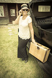 Happy 1920s Dressed Girl Holding Suitcase Next to Vintage Car