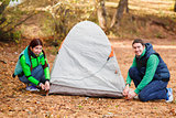 couple pitching tent in countryside