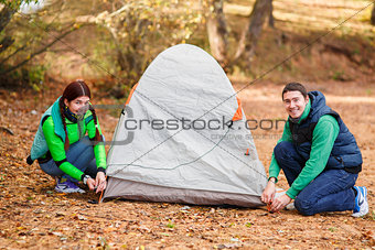 couple pitching tent in countryside