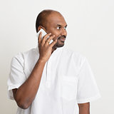 Mature casual business Indian man talking on phone