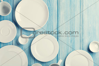 Empty plates and bowls on blue wooden background