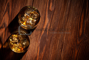 Glasses of whiskey with ice on wood