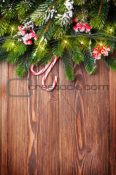 Fir tree branch with christmas lights and candy canes on wood