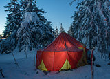 winter forest and illuminated tent