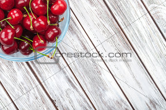 cherries in a glass bowl on a white wooden background