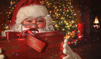 Closeup of Santa holding gift with Christmas scene in background