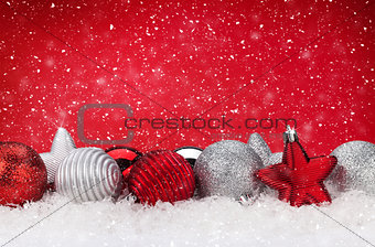 Christmas red background with baubles in snow