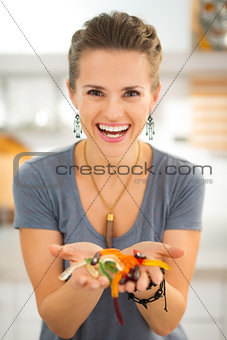 Woman holding in hand colorful halloween gummy worm candies.