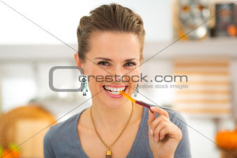 Smiling young woman eating halloween gummy worm candy