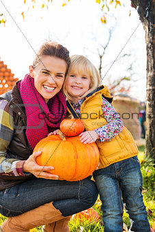 Portrait of woman and child holding pumpkins in autumn outdoors