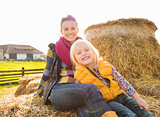 Portrait of beautiful woman and cute girl sitting on hay on farm