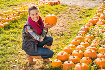 Portrait of smiling woman choosing pumpkin on farm