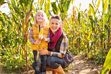 Portrait of happy mother and child staying in corn field on farm