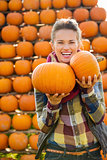 Portrait of smiling beautiful woman holding pumpkins on farm