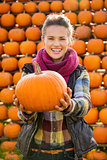 Portrait of smiling beautiful woman holding pumpkins on farm