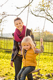Portrait of smiling woman and swinging child in autumn outdoors