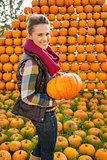 Portrait of smiling woman holding pumpkin on farm