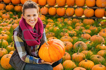 Portrait of smiling woman sitting and holding big pumpkin