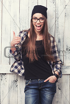Hipster girl in glasses and black beanie with thumbs up
