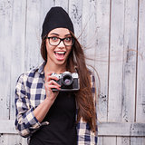 Hipster girl in glasses and black beanie with vintage camera