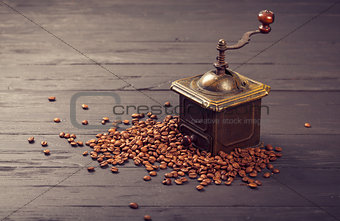Old vintage coffee mill on roasted hot beans