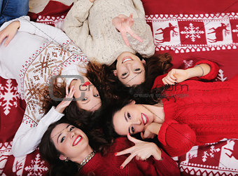 Smiling Happy girl friends group in New Year's sweater lying down on the floor  Having fun together at winter holiday time