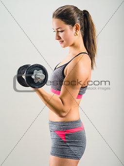 Young woman doing single dumbbell curl