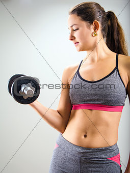Young woman concentrating on dumbbell curl