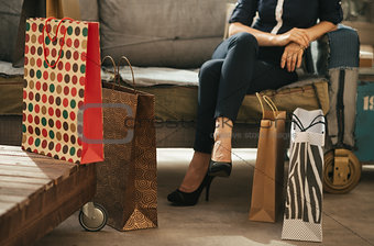 Close up on shopping bags and woman on couch in background