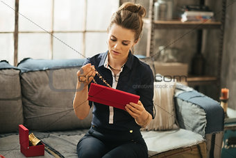 Wealthy woman sitting on couch in loft and unpacking jewelry box