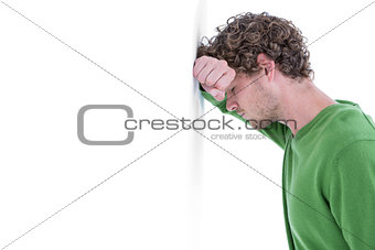Sad casual man leaning against wall