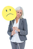 Businesswoman holding sad smiley face