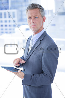 Businessman holding a tablet and looking at the camera
