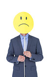 Businessman with sad smiley faced balloon at office desk