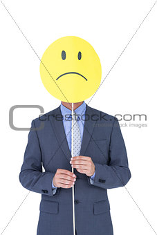 Businessman with sad smiley faced balloon at office desk