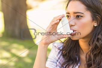 Pretty brunette using inhaler