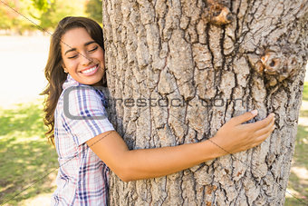 Pretty brunette hugging tree