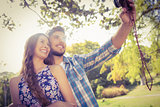 Cute couple doing selfie with retro camera in the park