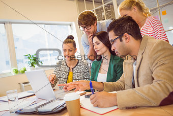 Happy creative business team using laptop in meeting