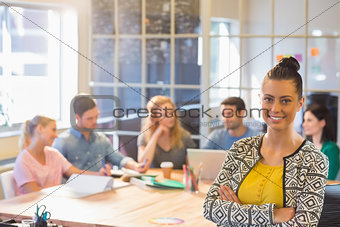Smiling businesswoman with colleagues in background at office