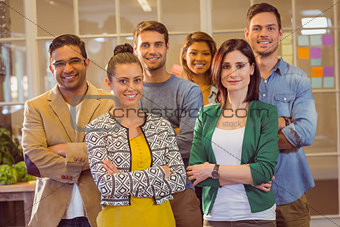 Happy business team smiling at camera with arms crossed