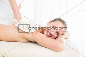 Peaceful brunette enjoying an exfoliating back massage