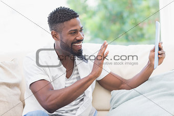 Man using his tablet on couch for video chat