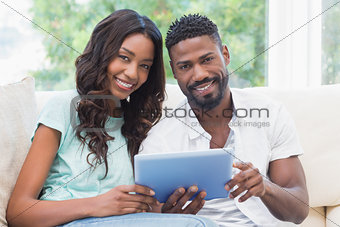 Happy couple using tablet together on the couch