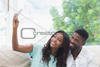 Happy couple on the couch taking selfie