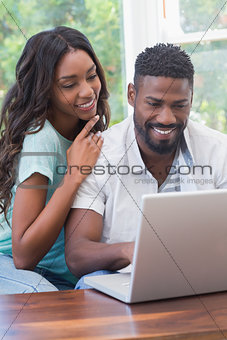 Happy couple on the couch using laptop
